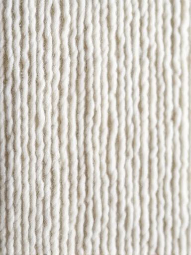 Tapisserie texturée abstraite dans des tons gris et crème, mettant en valeur la texture du fil